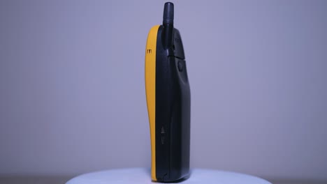 Gelbes-Mobiltelefon-Nokia-5110-Mit-Externer-Antenne,-Das-Sich-Auf-Einem-Drehteller-Mit-Weißem-Hintergrund-Dreht
