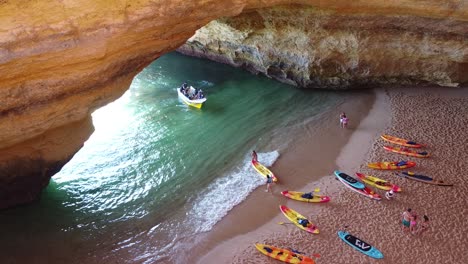 Benagil-Cave,-Algarve,-Portugal---Aerial-Drone-Shot-inside-the-cave-with-tourists,-boat-and-kayaks