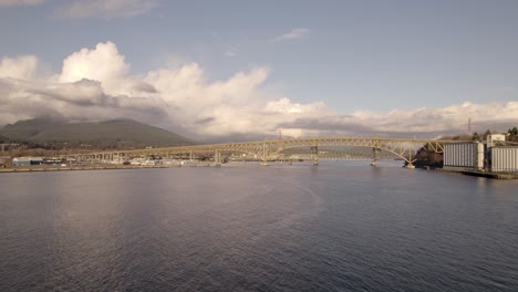 Arial-forward-over-Burrard-Inlet-waters-with-Ironworkers-Memorial-Bridge-in-background,-Vancouver-in-Canada