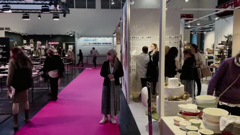 Slow-panning-shot-of-female-customer-with-face-mask-shopping-on-trade-fair-during-coronavirus-pandemic---trade-fair-hall-in-2022-in-Munich,Germany