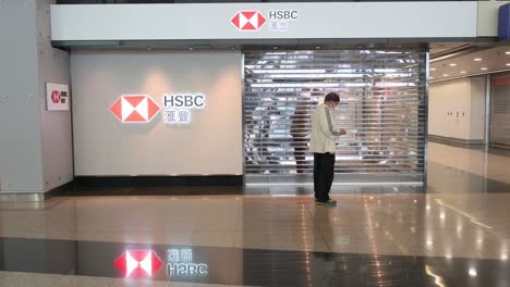 A-man-stands-in-front-of-a-closed-British-multinational-banking-and-financial-company,-HSBC-Bank,-in-Hong-Kong-International-Airport-as-most-businesses-shutdown-due-to-the-Covid-19-variant-spread