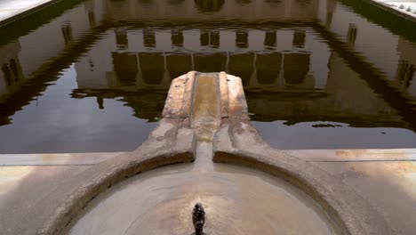 Slow-motion-tilt-up-over-water-pond-reflections-inside-Alhambra-Palace-in-Spain