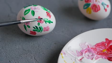 Woman-hands-decorating-Easter-eggs-using-natural-materials,-flowers-paper-pattern,-brush-and-egg-glaire-to-glue-the-patterns