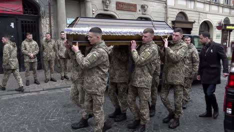 Ukrainian-soldiers-carry-a-fallen-comrade’s-coffin-on-their-shoulders-past-onlookers-towards-the-entrance-of-the-Church-of-the-Most-Holy-Apostles-Peter-and-Paul