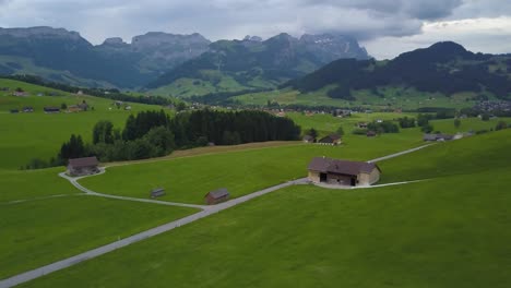 Drone-Volando-Sobre-El-Verde-Valle-Suizo-Con-Montañas-En-Segundo-Plano