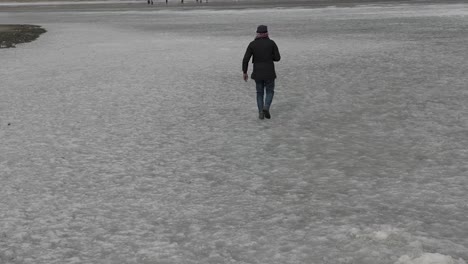 View-Of-Adult-Male-Walking-Across-Frozen-Khalti-Lake