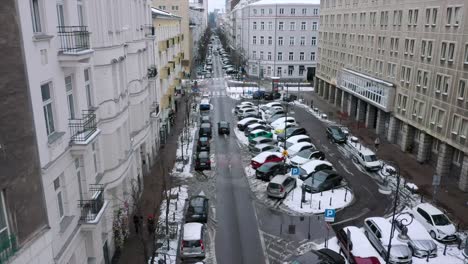 Aerial-view-of-a-car-driving-on-snowy-streets-of-Warsaw,-winter-in-Poland---Static,-drone-shot