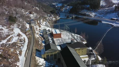 Stromleitungen-Hängen-über-Dem-Wasserkraftwerk-Nore-I-Und-Dem-Rodberg-Staudamm-–-Luftaufnahme-Des-Stakraft-Kraftwerks-Mit-Infrastruktur-In-Rodberg,-Norwegen