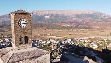 Gjirokaster-Castle,-Albania---Aerial-of-Clock-Tower,-Cityscape-and-Mountain-Landscape