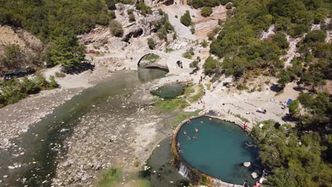 Menschen-Schwimmen-In-Den-Heißen-Quellen-Und-Thermalbädern-Von-Permet,-Albanien---Luftaufnahme