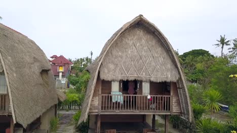 Stunning-aerial-view-flight-panorama-curve-flight-drone-footage-of-a-girl-in-a-lokal-Bali-beach-hut