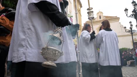 Una-Monaguillo-Balancea-Un-Incensario-Que-Quema-Incienso-Para-Despejar-El-Camino-Durante-Una-Procesión-De-Semana-Santa-En-Cádiz,-España.