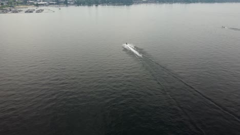 Crane-drone-shot-of-a-jet-skier-driving-towards-the-marina-on-Lake-Payette-in-McCall,-Idaho
