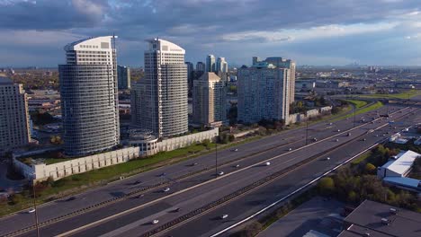 Residential-condominium-apartment-buildings-along-Highway-401-in-Toronto,-Ontario-with-busy-traffic-and-transport-trucks