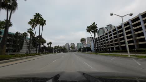 Driving-down-an-empty-road-in-Long-Beach,-California---driver-point-of-view-looking-over-the-hood-of-the-car