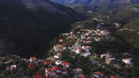 Aerial-of-historic-old-town-of-Himara-amidst-huge-steep-mountains-of-Ceraunian,-Albania