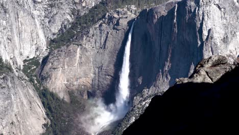 High-Yosemite-falls-cascading-drop-from-behind-rock-cliff-wall,-Dolly-left-shot