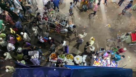 Street-market-vendors-and-many-people-walking-around-at-night,-top-down-view