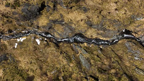 Drone-tracking-river-flowing-down-rugged-rocky-Italian-alp-mountain-hillside