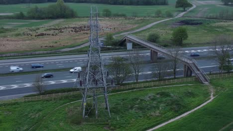 Speeding-traffic-passing-pylon-electricity-tower-on-M62-motorway-aerial-right-orbit-view