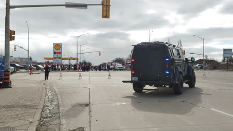 Armored-police-car-parked-at-an-intersection-with-blue-flashing-lights-and-blocking-the-road