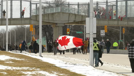 12-De-Febrero-De-2022---Manifestantes-Del-Convoy-De-La-Libertad-Caminando-Por-La-Carretera-Con-Una-Gran-Bandera-Canadiense