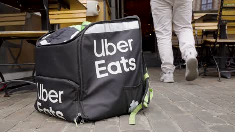 Uber-Eats-bag-in-front-of-restaurant-as-the-rider-walks-in-to-pick-up-food-order---Slow-motion