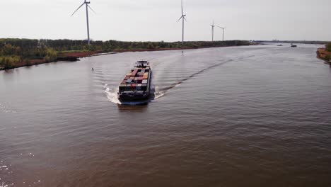 Luftaufnahme-über-Oude-Maas-Mit-Dem-Sich-Nähernden-Frachtschiff-Petran-Mit-Windmühlen-Im-Hintergrund