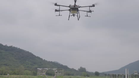 Agricultural-drone-flying-in-the-air,-spraying-liquid-pesticides-over-rice-field-in-China