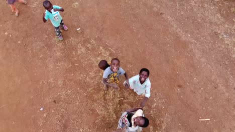 Niños-Africanos-Sonrientes-Felices,-Saludando-A-La-Cámara-De-Arriba,-Vista-De-Drones