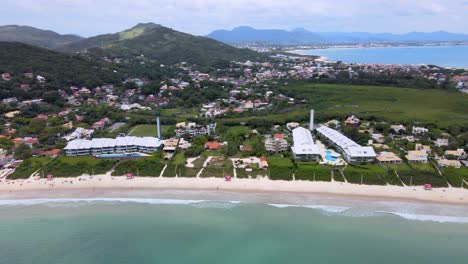 Aerial-drone-view-of-tourist-beach-with-several-summer-houses-facing-the-sea-with-lots-of-vegetation-and-nature