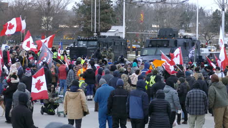 Static-shot-of-massive-crowds-getting-hold-back-by-armored-police-vehicles-during-a-demonstration