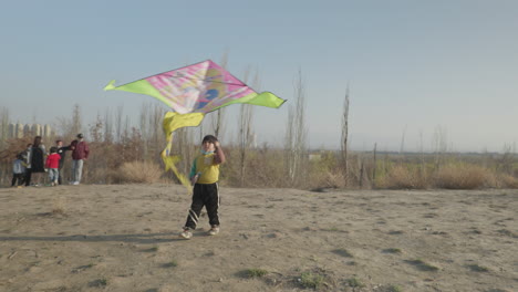 Süßes-Uigurisches-Kind,-Das-Mit-Einem-Drachen-Auf-Einem-Hügel-In-Hotan,-Xinjiang,-China-Spielt
