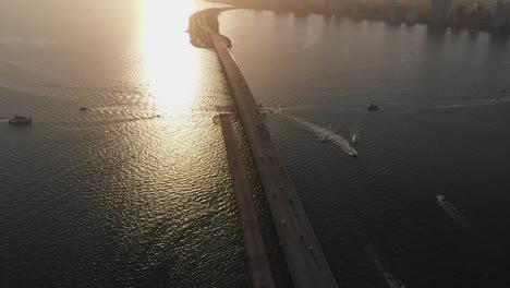 Aerial-view-of-Miami-cityscape,-tilt-down-reveals-William-Powell-Bridge,-sunset