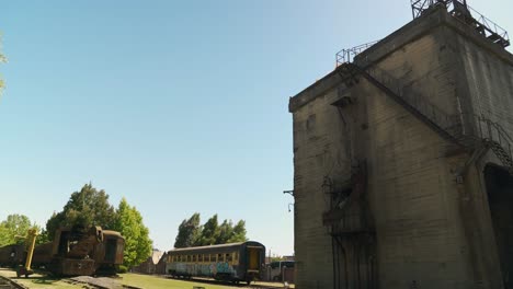 Cinematic-shot-of-an-old-coal-mining-control-tower-with-rusty-cars-and-railroad-tracks-at-the-Railway-Museum-in-Temuco,-Chile