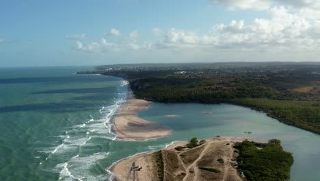 Aerial-drone-wide-shot-of-the-beautiful-coastline-of-Gramame-where-the-ocean-meets-the-river-near-the-tropical-beach-capital-city-of-Joao-Pessoa-in-Paraiba,-Brazil-on-a-warm-summer-day
