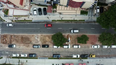 Bird's-eye-top-view-aerial-drone-shot-of-a-small-city-street-intersection-in-the-tropical-beach-capital-city-of-Joao-Pessoa,-Paraiba,-Brazil-with-pedestrians-and-cars-passing-by