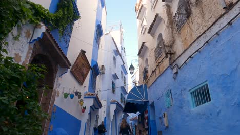 Tilt-down-reveals-mesmerizing-Chefchaouen-narrow-cobblestone-street-adorned-with-blue-facades