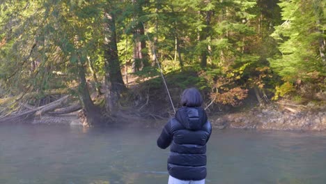 Back-View-Of-A-Woman-In-Puffer-Jacket-Fishing-In-The-River-Forest