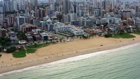 Rotating-aerial-drone-shot-of-the-famous-tourist-destination-Tambaú-beach-in-the-tropical-capital-city-of-Joao-Pessoa-in-Paraiba,-Brazil-with-vibrant-tents-lined-up-for-visitors