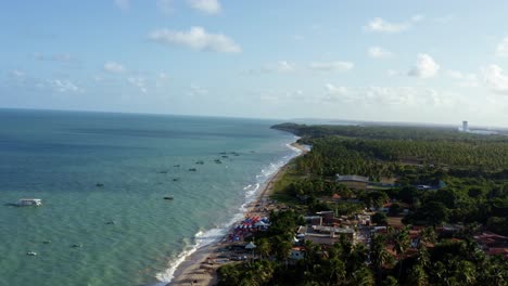 Right-truck-aerial-drone-shot-of-the-beautiful-tropical-Penha-beach-coastline-near-the-capital-city-of-Joao-Pessoa-in-Paraiba,-Brazil-with-waves-crashing-into-the-sand-and-small-fishing-boats-docked