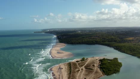 Dolly-out-aerial-drone-wide-shot-of-the-beautiful-coastline-of-Gramame-where-the-ocean-meets-the-river-near-the-tropical-beach-capital-city-of-Joao-Pessoa-in-Paraiba,-Brazil-on-a-warm-summer-day