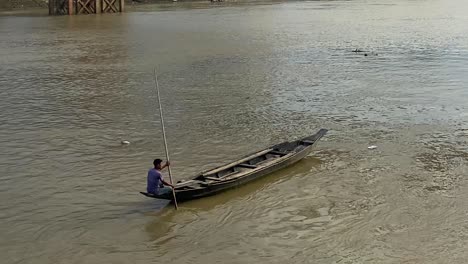 Ein-Geschickter-Bootsmann-Rudert-Mit-Seinem-Holzboot-Durch-Die-Ruhigen-Gewässer-Eines-Asiatischen-Flusses