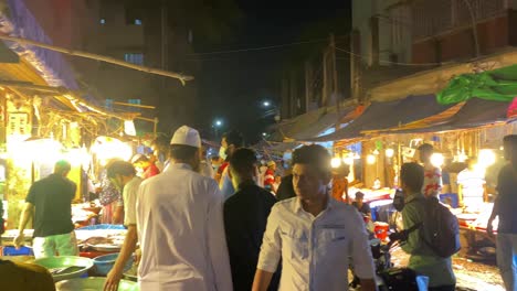 Panning-shot-of-a-busy-and-colorful-night-fish-bazaar-in-Bangladesh,-with-vibrant-lights-and-bustling-activity