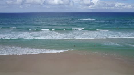 Menschen-Schwimmen-Im-Meer-Mit-Wellen,-Die-Auf-Das-Sandige-Ufer-Am-Miami-Beach-Rollen,-Einem-Berühmten-Reiseziel-An-Der-Gold-Coast,-Queensland