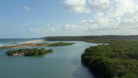 Dolly-in-aerial-drone-wide-shot-of-the-large-winding-tropical-Gramame-river-where-it-meets-the-ocean-near-the-tropical-beach-capital-city-of-Joao-Pessoa-in-Paraiba,-Brazil-on-a-warm-summer-day
