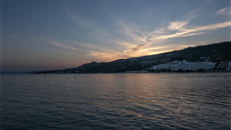 Zeitrafferaufnahme-Eines-Ferienortes-In-Der-Ferne-Am-Ufer-Des-Schwarzen-Meeres-In-Varna,-Bulgarien,-Mit-Sonnenuntergang-Im-Hintergrund-Und-Leuchtend-Gelbem-Himmel