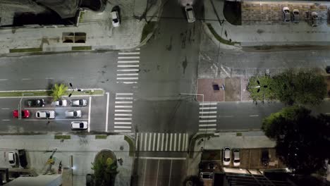 Aerial-drone-bird's-eye-top-shot-of-a-small-street-intersection-surrounded-by-apartments-in-the-tropical-beach-capital-city-of-Joao-Pessoa,-Paraiba,-Brazil-during-a-warm-summer-night