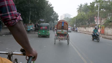 First-person-view-from-a-rickshaw-passenger-seat-as-a-rickshaw-puller,-or-driver,-drives-through-the-traffic-at-the-busy-roads-of-Dhaka