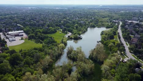 Drone-flying-over-Markham-park-with-a-pond-on-it-on-a-summer-day